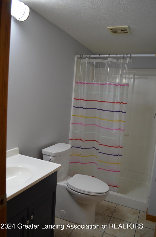 bathroom featuring curtained shower, tile patterned flooring, a textured ceiling, toilet, and vanity