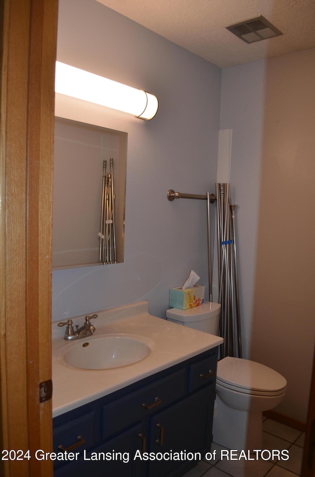 bathroom featuring tile patterned floors, vanity, a textured ceiling, and toilet