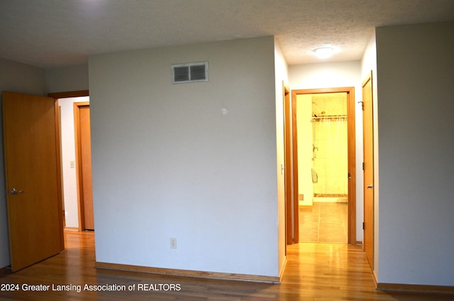 hallway featuring a textured ceiling and light hardwood / wood-style floors