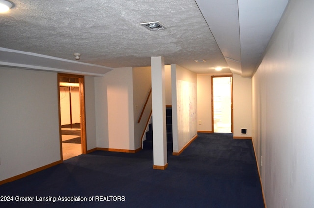 basement featuring dark carpet and a textured ceiling