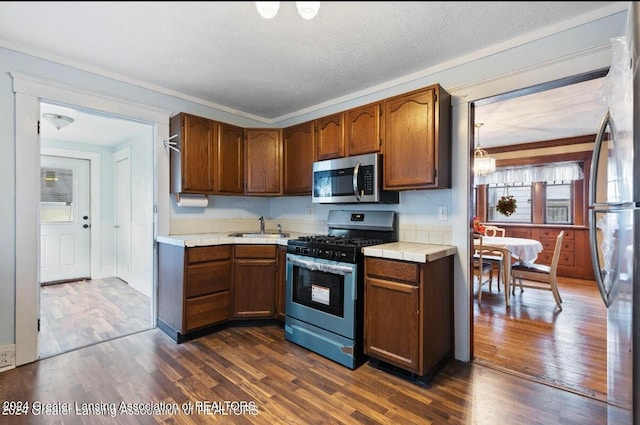 kitchen featuring tile counters, stainless steel appliances, dark hardwood / wood-style flooring, a textured ceiling, and sink