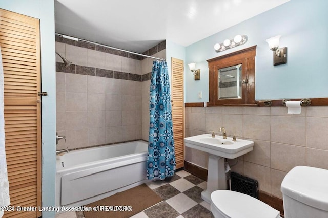 bathroom with tile walls, shower / bath combo, and toilet