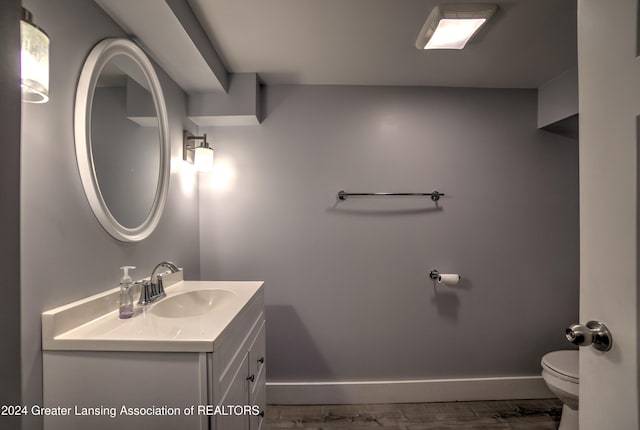 bathroom with hardwood / wood-style flooring, vanity, and toilet