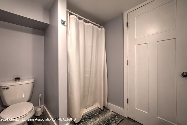 bathroom with toilet, wood-type flooring, and curtained shower