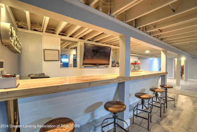 bar featuring hardwood / wood-style floors and wood counters