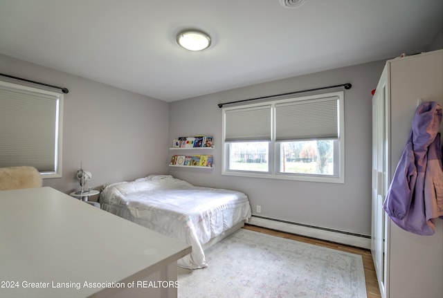 bedroom with light wood-type flooring and a baseboard radiator