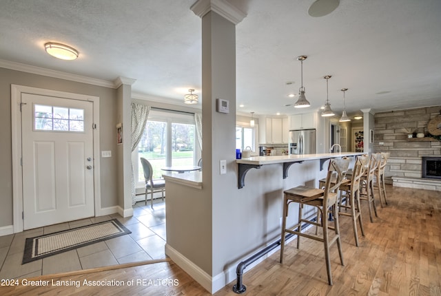 kitchen featuring white cabinetry, stainless steel refrigerator with ice dispenser, light hardwood / wood-style flooring, and a breakfast bar area