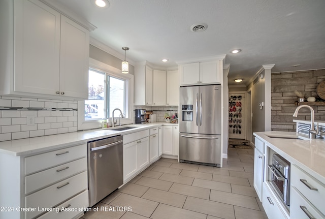 kitchen featuring pendant lighting, appliances with stainless steel finishes, white cabinetry, and sink