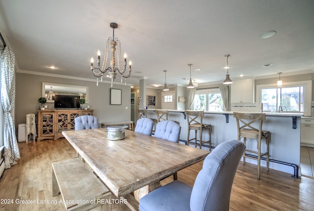 dining area featuring ornamental molding, light wood-type flooring, and a notable chandelier