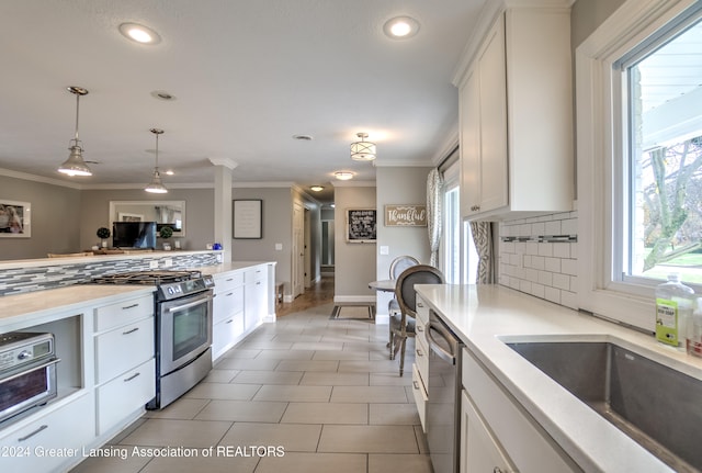 kitchen featuring crown molding, white cabinetry, appliances with stainless steel finishes, pendant lighting, and decorative backsplash