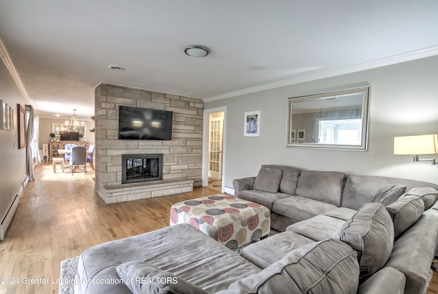 living room featuring a stone fireplace, a chandelier, crown molding, and light hardwood / wood-style flooring