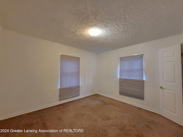 carpeted empty room with a textured ceiling