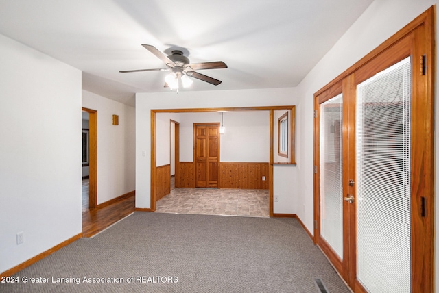 unfurnished room with ceiling fan, light colored carpet, and wooden walls