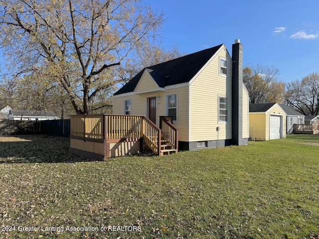 rear view of house with a deck, a garage, a yard, and an outdoor structure