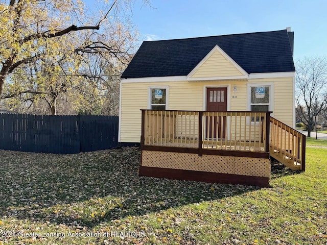 rear view of property featuring a wooden deck and a lawn