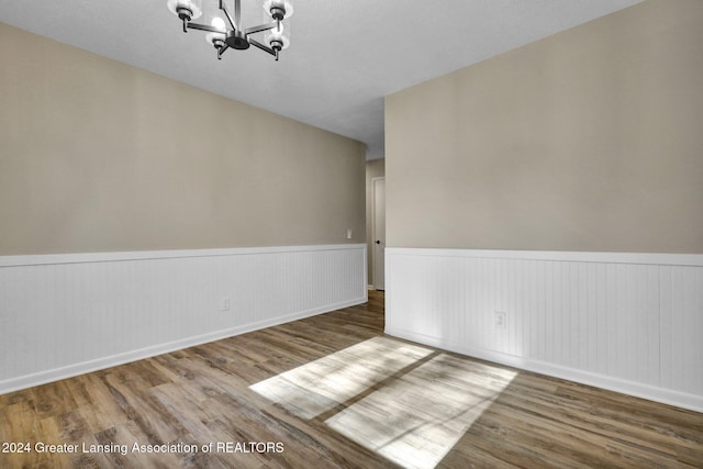 empty room featuring a chandelier and hardwood / wood-style flooring