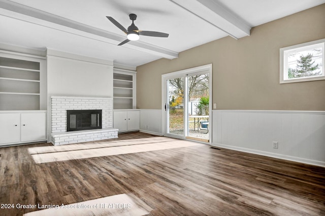 unfurnished living room with a fireplace, beam ceiling, ceiling fan, and wood-type flooring