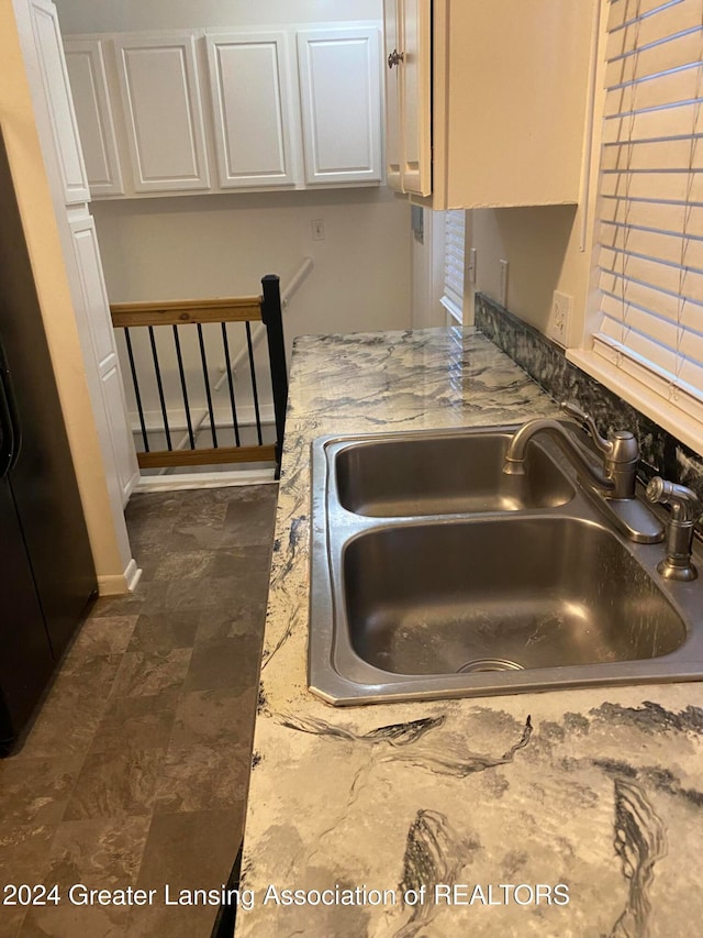 room details featuring sink, light stone counters, and white cabinets