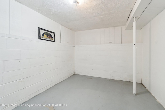 basement with concrete block wall and a textured ceiling