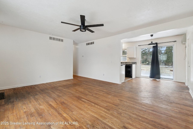 unfurnished living room with a ceiling fan, visible vents, and wood finished floors