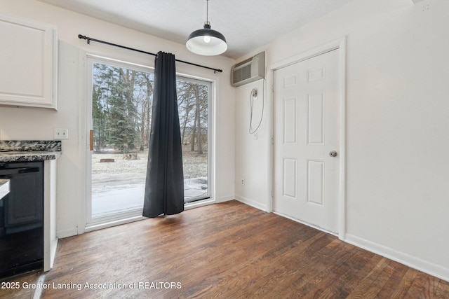 interior space with an AC wall unit, baseboards, and wood finished floors