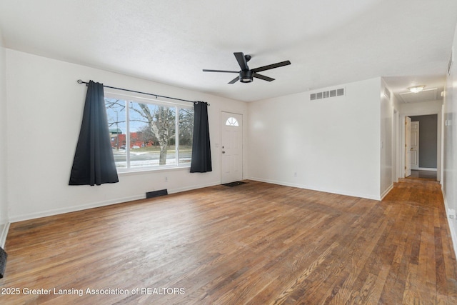 unfurnished living room featuring a ceiling fan, baseboards, visible vents, and wood finished floors