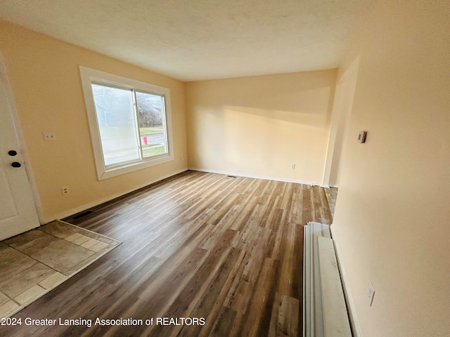 unfurnished room with hardwood / wood-style floors and a textured ceiling