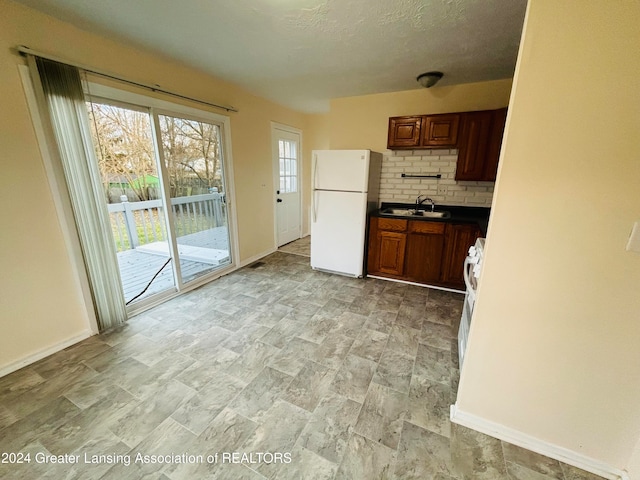 kitchen with tasteful backsplash, white appliances, sink, and a textured ceiling