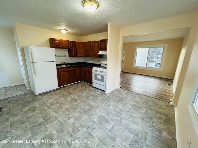 kitchen with backsplash, a textured ceiling, sink, light hardwood / wood-style floors, and white appliances