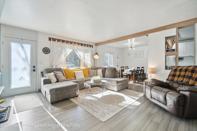 living room featuring beamed ceiling, hardwood / wood-style flooring, and a chandelier