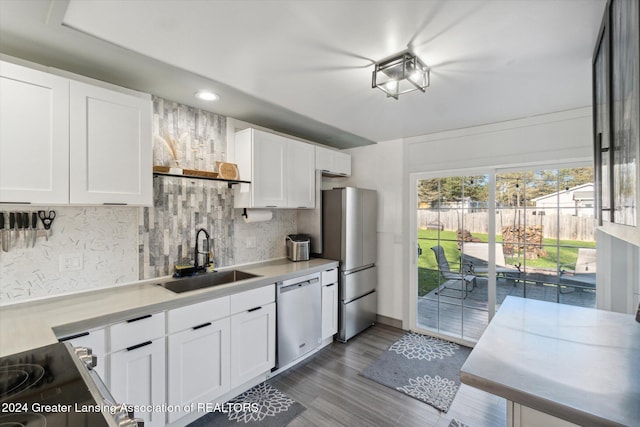 kitchen featuring wood-type flooring, white cabinetry, appliances with stainless steel finishes, decorative backsplash, and sink