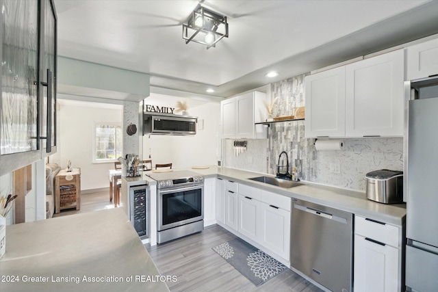 kitchen featuring light wood-type flooring, appliances with stainless steel finishes, sink, and white cabinets