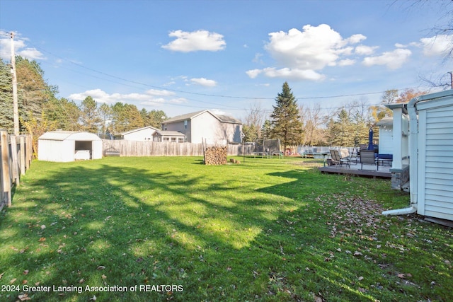 view of yard with a shed, a wooden deck, and a trampoline