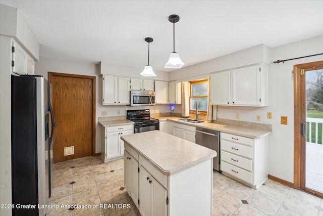 kitchen with pendant lighting, white cabinets, sink, appliances with stainless steel finishes, and a kitchen island