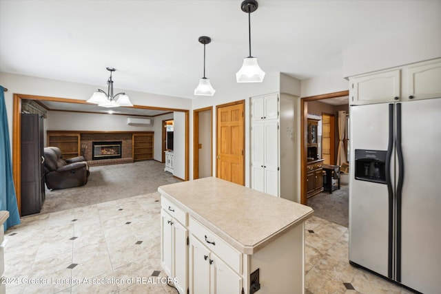 kitchen with white cabinets, stainless steel refrigerator with ice dispenser, a center island, and a fireplace