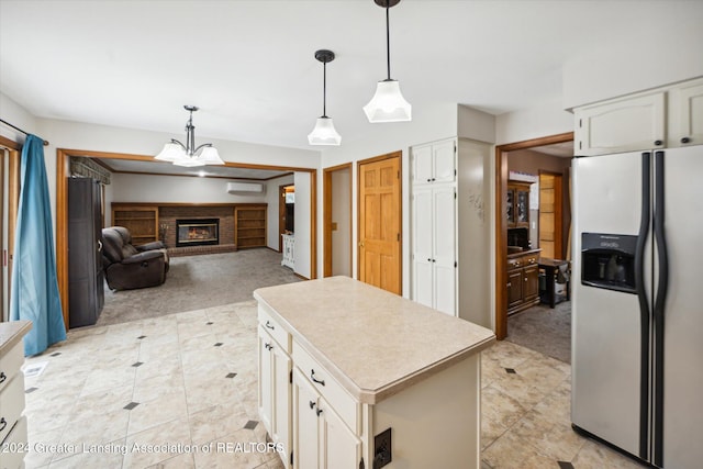 kitchen featuring a kitchen island, white cabinetry, stainless steel refrigerator with ice dispenser, and a brick fireplace