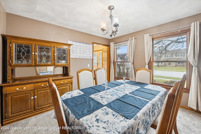 dining room with light carpet and a notable chandelier