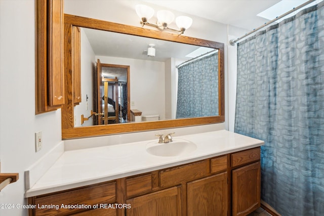 bathroom featuring a shower with shower curtain, vanity, a skylight, and toilet