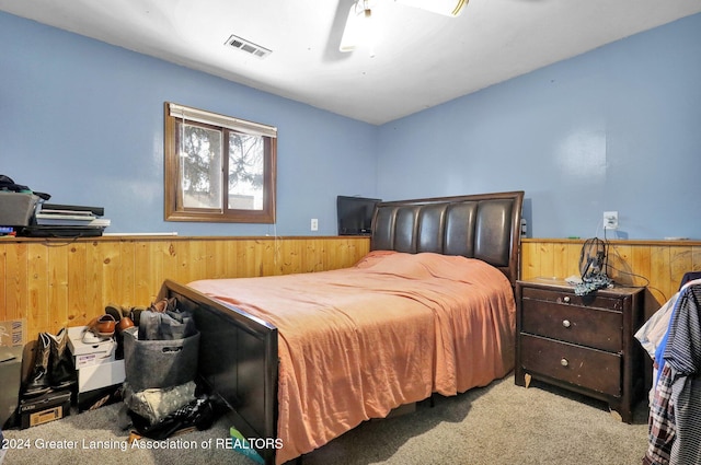 bedroom featuring wooden walls and light carpet