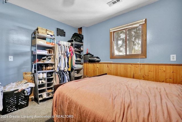 bedroom with wooden walls and carpet