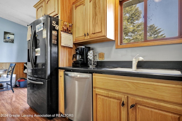 kitchen featuring dishwasher, black refrigerator with ice dispenser, sink, and light hardwood / wood-style floors