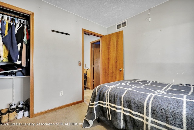 carpeted bedroom with a textured ceiling and a closet