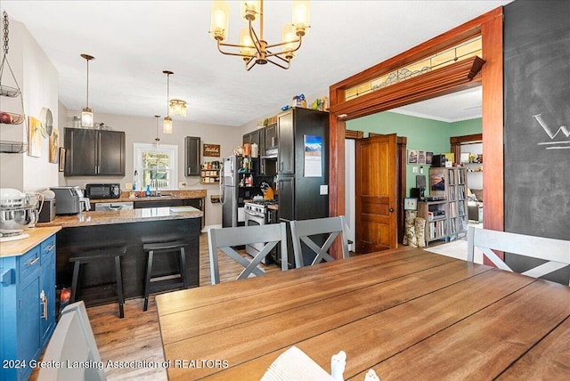 dining area with a chandelier, sink, light wood-type flooring, and crown molding