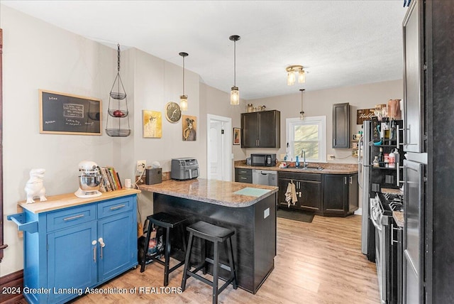 kitchen with stainless steel appliances, kitchen peninsula, a kitchen bar, blue cabinetry, and light hardwood / wood-style flooring