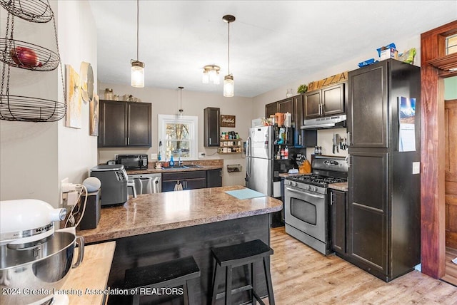 kitchen with dark brown cabinetry, hanging light fixtures, a kitchen breakfast bar, light wood-type flooring, and appliances with stainless steel finishes