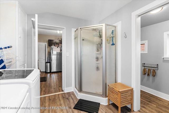 bathroom with a shower with door, hardwood / wood-style flooring, and washer and dryer