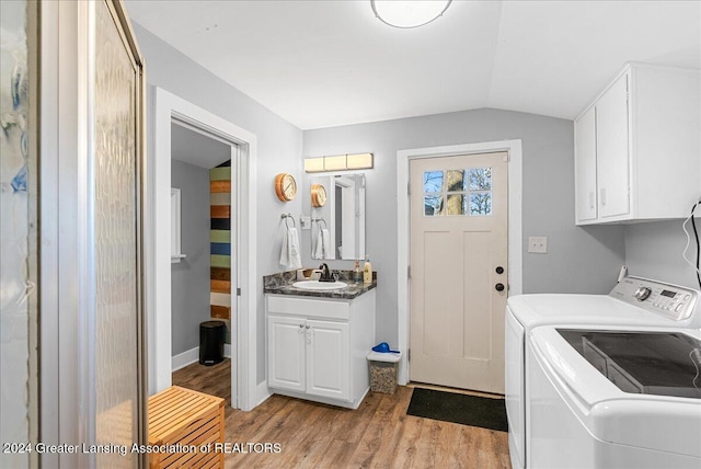 washroom with cabinets, sink, washer and dryer, and light hardwood / wood-style flooring