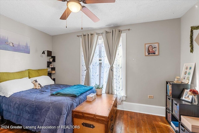 bedroom featuring dark hardwood / wood-style flooring, a textured ceiling, and ceiling fan