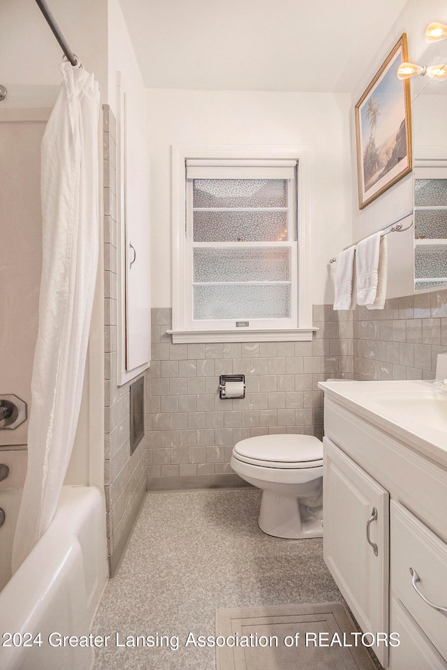 full bathroom featuring vanity, toilet, shower / bath combo with shower curtain, and tile walls