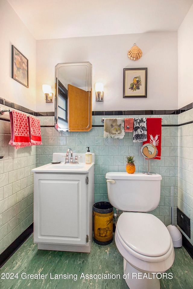 bathroom featuring vanity, tile walls, and toilet